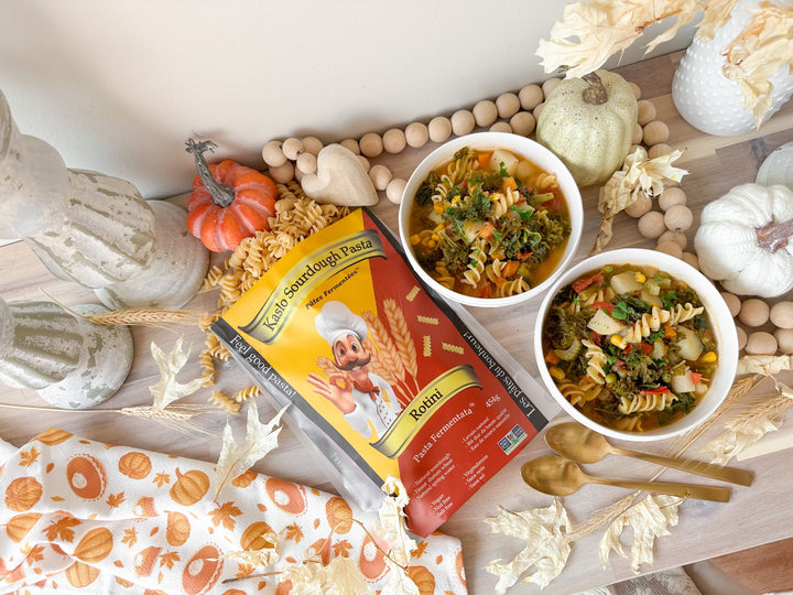 Plant-based Hearty Garden Vegetable Soup served in two small bowls, with a bag of Kaslo Sourdough Rotini placed beside them.